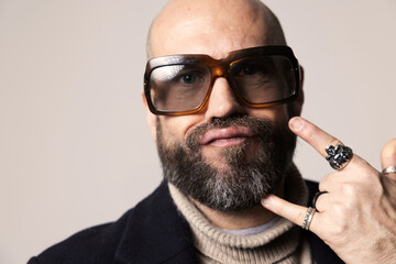 Portrait of mature bald man with beard, wearing sunglasses posing confidently indoors.