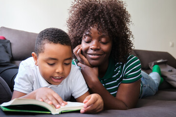 Obraz premium Mother and son bonding over a book on a cozy couch