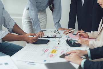Collaborative Brainstorming:  A diverse team of business professionals huddle around a table,...