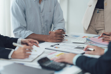 Collaborative Business Meeting: Hands actively engaged in analyzing financial charts and data during a focused business meeting, showcasing teamwork and strategic planning.