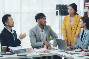 Business Meeting Collaboration: A diverse team of professionals engages in a lively discussion around a table in a modern office setting, showcasing collaboration, problem-solving.