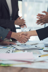Sealed Deal: A close-up shot focusing on a firm handshake between two businesspeople across a table...