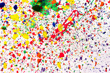 Drops of acrylic paints of different colors are randomly splashed on a white background.