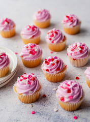 Small cupackes with pink frosting and hearts on white background.