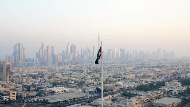 Aerial view of the United Arab Emirates (UAE) national flag waving  with the Dubai skyline in background