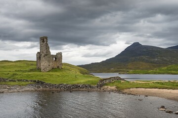 Ruins of Ardvreck Castle on a peninsula in the lake of Loch Assynt, in front of the 764m mountain...