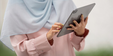 Muslim business woman in hijab using tablet for work and communication.