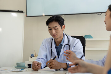 Young diverse doctor taking notes and analyzing data during a team meeting.