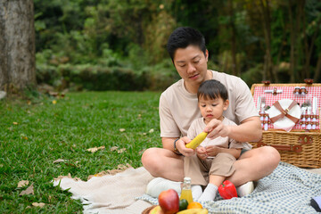 Happy father and his little child enjoying a picnic in the park.