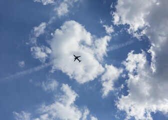 Silhouette of an airplane in front of clouds in the blue sky, Germany, Europe