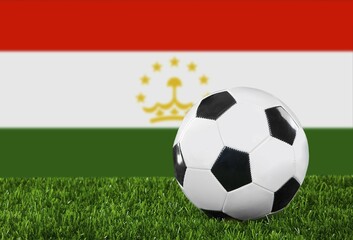 The Tajik flag and soccer ball on the green grass