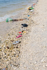 Garbage trash rubbish waste being washed to the shoreline by sea waves.