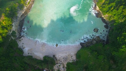 Drone view of coral hills on the edge of the sea with trees, coastal sand coral cliffs, and waves from the ocean at Sawangan Beach, Kebumen, Central Java