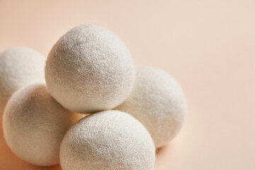 Close-up of stacked wool dryer balls on a beige background. Eco-friendly, reusable laundry accessory for reducing static, wrinkles, and drying time