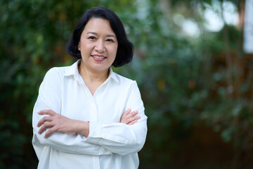Portrait of smiling middle aged Asian business women in natural background
