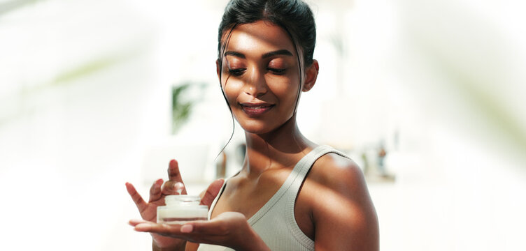 Bathroom, woman and apply with cream for skincare, wellness and anti aging benefits for self care. Home, female person and cosmetics product with smile for moisturizer, lotion and sunscreen treatment