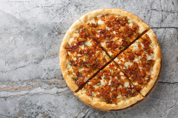 Homemade delicious French onion pizza with gruyere and mozzarella cheese, thyme and garlic close-up on a wooden board on the table. Horizontal top view from above