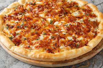 French onion pizza is basically a portable version of French onion soup, complete with both Gruyere and mozzarella cheese closeup on the wooden board on the table. Horizontal