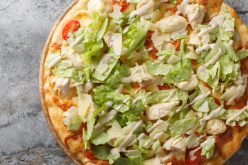 White Caesar pizza with chicken, lettuce, tomatoes, cheese and tender cream dressing closeup on the wooden board on the table. Horizontal top view from above