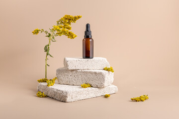 A bottle of fragrant oil on a stone podium. Essential oil or serum in a brown bottle with a...