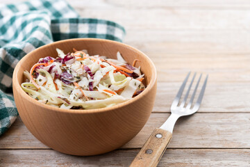 Coleslaw salad in wooden bowl on wooden table. Copy space