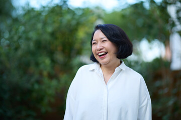 Portrait of smiling middle aged Asian business women in natural background