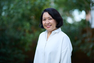 Portrait of smiling middle aged Asian business women in natural background