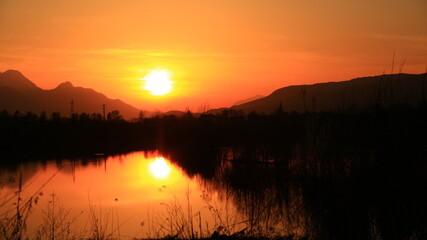 Sunset in the nature, near lake, among forests.