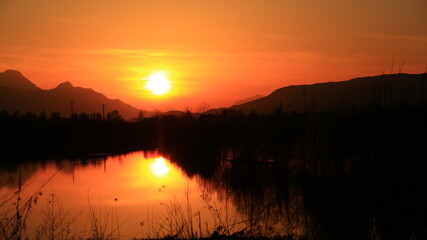 Sunset in the nature, near lake, among forests.