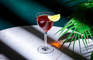 Irish Jack Rose alcoholic cocktail drink with Irish whiskey, calvados, lime juice, grenadine and lime wedge. Green background, hard light and shadows