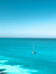Fototapeta premium A lone boat floating on calm waters near a rugged coastline. Concept of escape, solitude, and the boundless beauty of nature