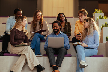 University students collaborating on project using laptop and notebooks