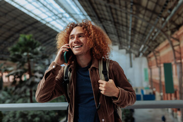 Happy tourist talking on smart phone at train station in madrid