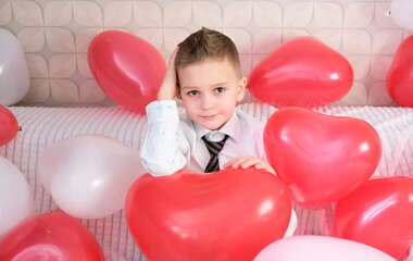 Portrait of sad child with red heart-shaped balloons. Valentine's Day concept. Angel Valentine.