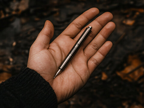 Close-up hand holding medical penlight professional diagnostic tool pupil throat examination sleek silver flashlight bright LED beam dark grip health beam blue optical battery vision durable macro