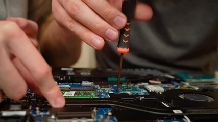 Hands tightening screws on notebook laptop motherboard, securing cooling system. Adjusting components with precision, ensuring stable hardware assembly. Repairing internal parts of laptop, focusing on