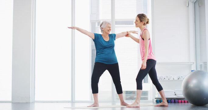 Yoga, instructor and help woman with stretching for fitness, body health or warrior pose for senior wellness. Assistance, pilates coach or exercise together for balance, physiotherapy or smile in gym
