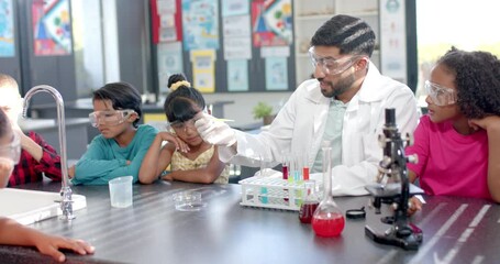 In a school laboratory, a biracial teacher demonstrates a science experiment