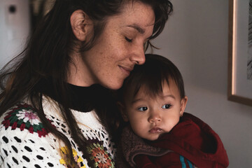 Tender sweet image of mother cuddling baby looking out window