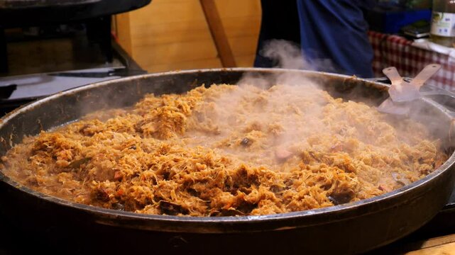 Polish dish - Bigos. A large portion of cabbage with sausage cooking in a pot outdoors