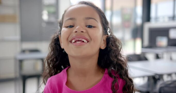 In school, smiling child with missing teeth in classroom, looking at camera