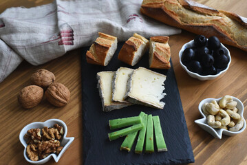 Slate serving board with cheese bread olives and walnuts