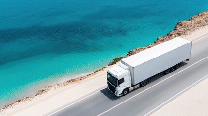 Aerial view of a white truck driving on a coastal road next to clear blue sea on a sunny day, showcasing efficient and scenic transport.