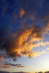 Dramatic sky with clouds illuminated from below by the late evening sun at sunset, landscape in...