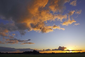 Dramatic sky with clouds illuminated from below by the late evening sun at sunset, landscape in Oberalsterniederung Nature Reserve, Tangstedt, Schleswig-Holstein, Germany, Europe
