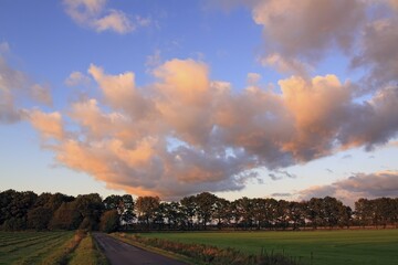 Dramatic sky with clouds illuminated in red light from the late evening sun at sunset, landscape in...