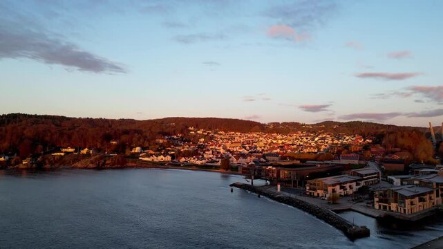 Stunning golden sunset over Larvik, Norway, highlighting the coastal town, modern waterfront, and charming hillside houses.