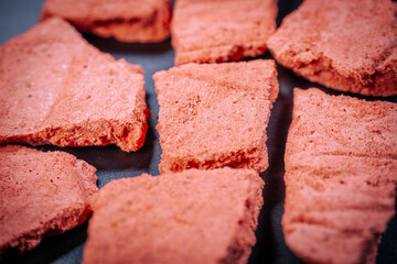 Macro shot of pinkish red freeze-dried berry snack pieces, highlighting their crunchy texture and rich color against a dark background. Perfect for food, snacks, and healthy eating themes.