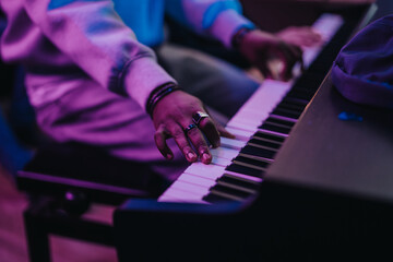A musician skillfully plays the piano, highlighting finger placement and musical expression under colorful lighting. This image captures the passion and talent of performing arts.