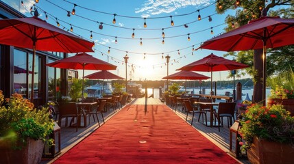 Scenic outdoor dining area with red umbrellas at sunset, vibrant flowers, and calm water view